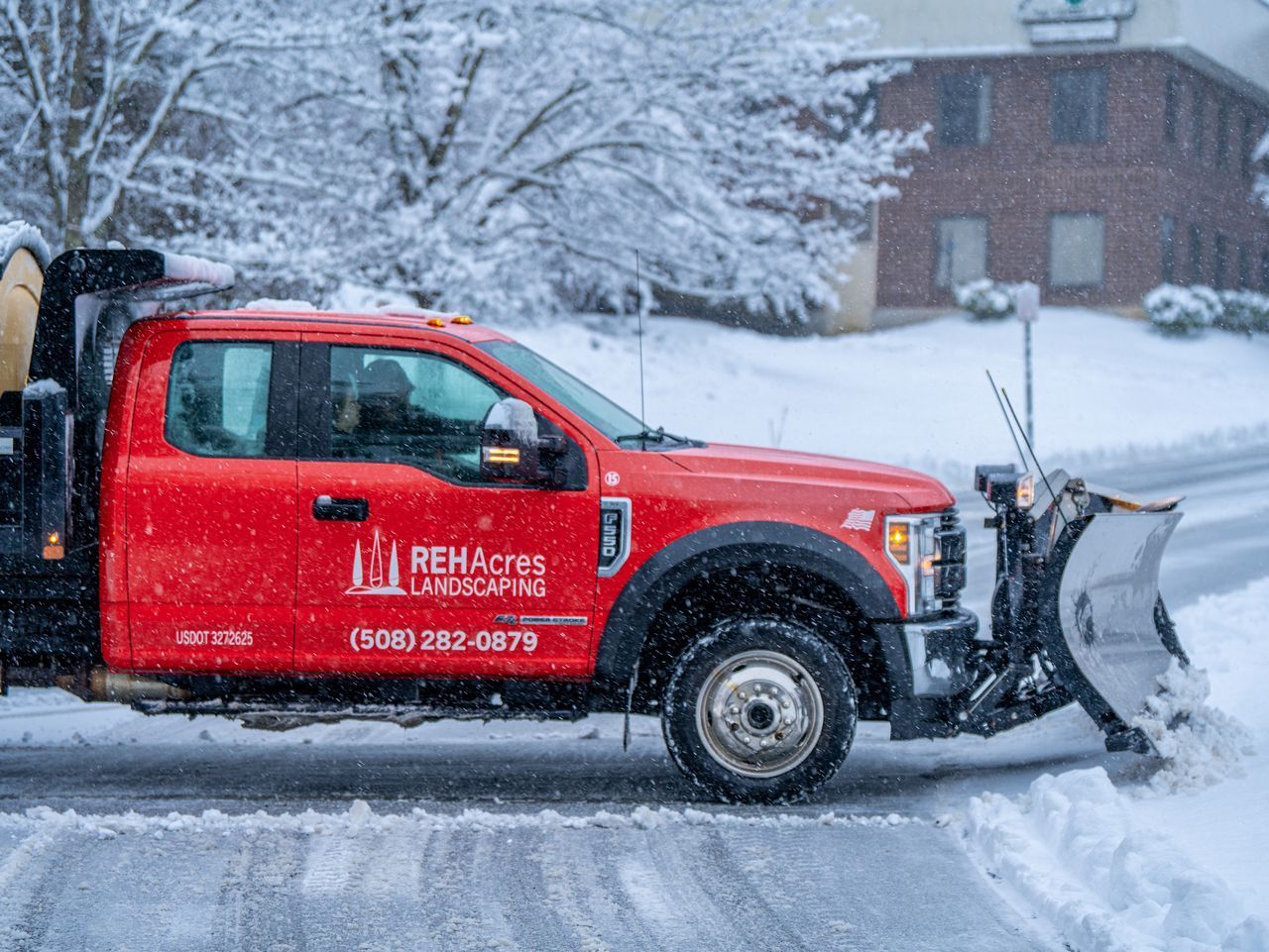 Red snowplow truck clearing a snowy residential street