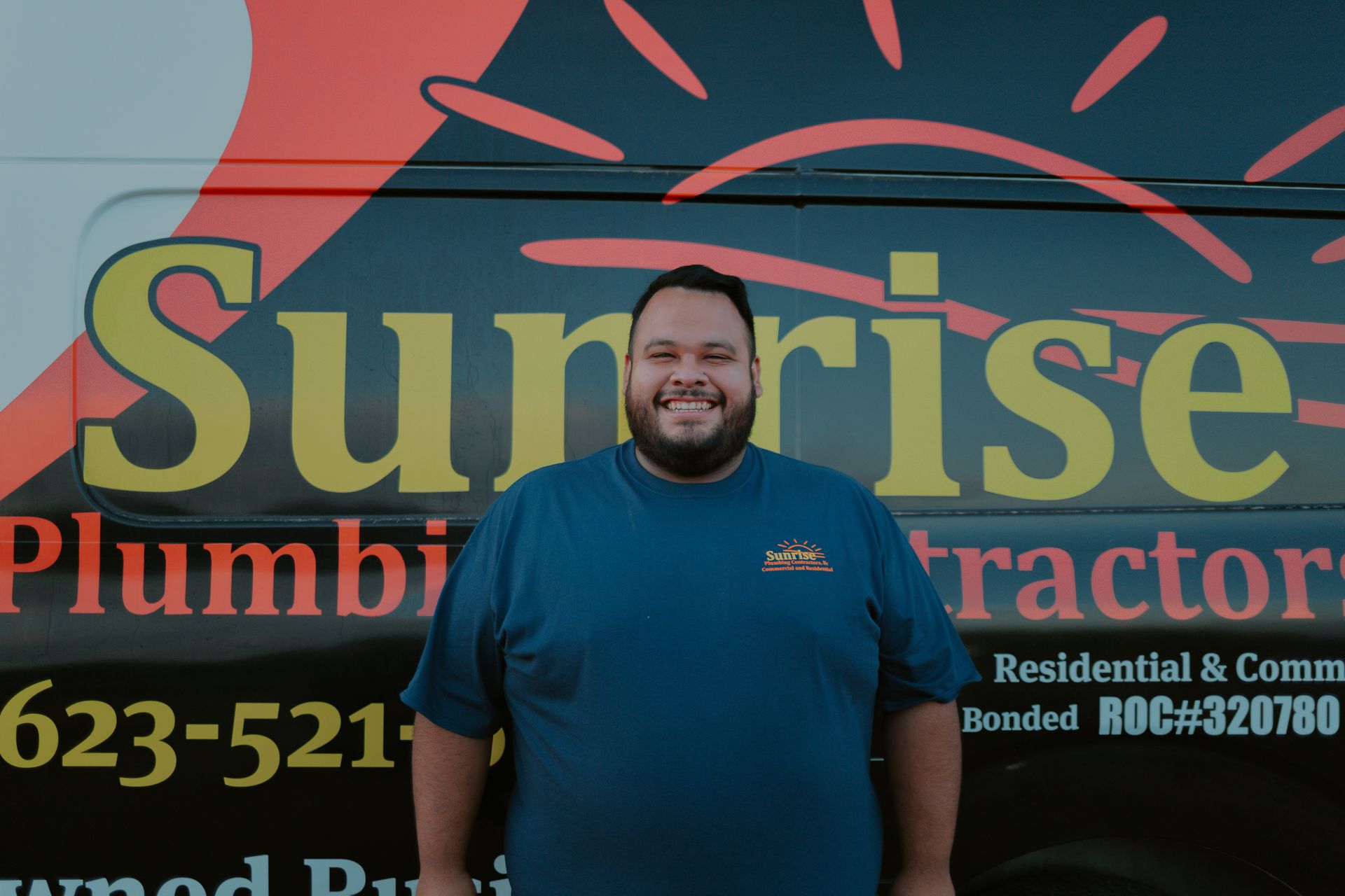 Man smiling in front of a plumbing van. 