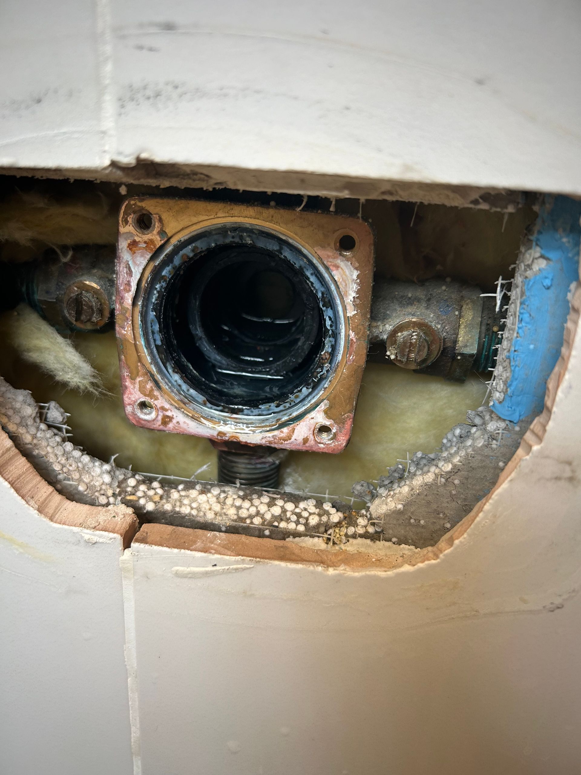 Copper plumbing fixture set into wall cavity.
