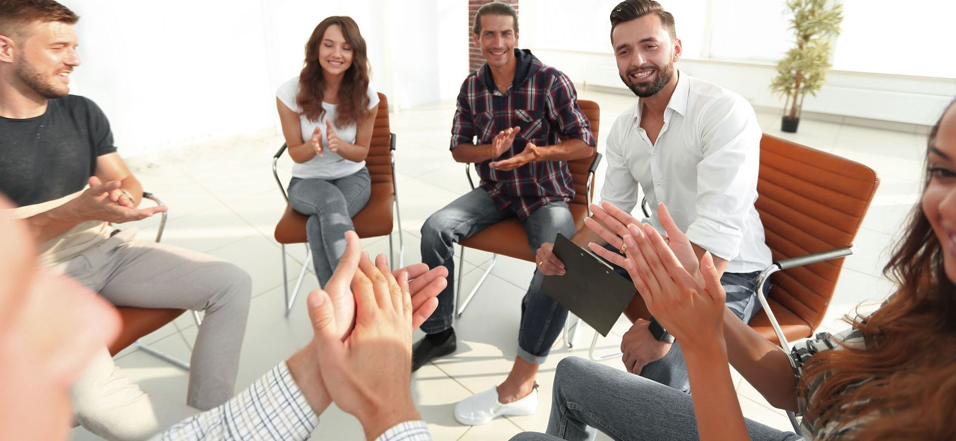 A group of people are sitting in a circle clapping their hands.