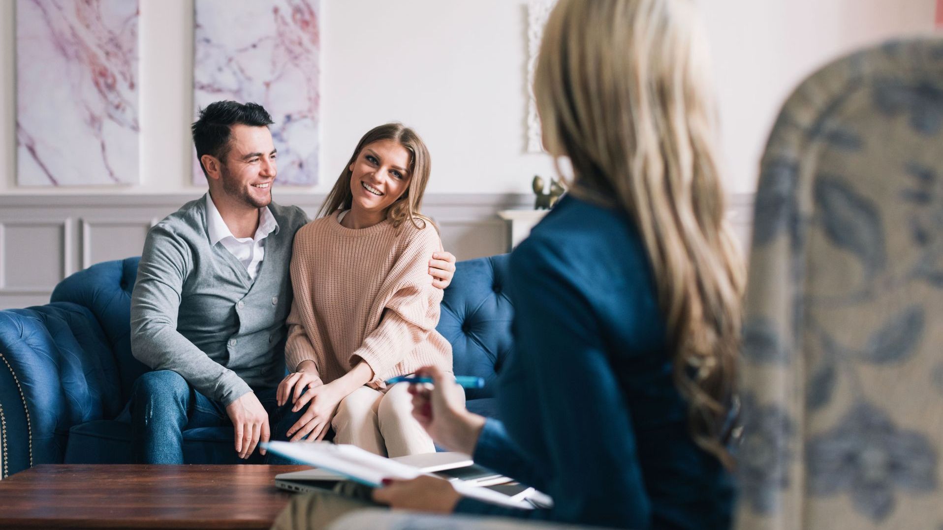 A man and a woman are sitting on a couch talking to a woman.