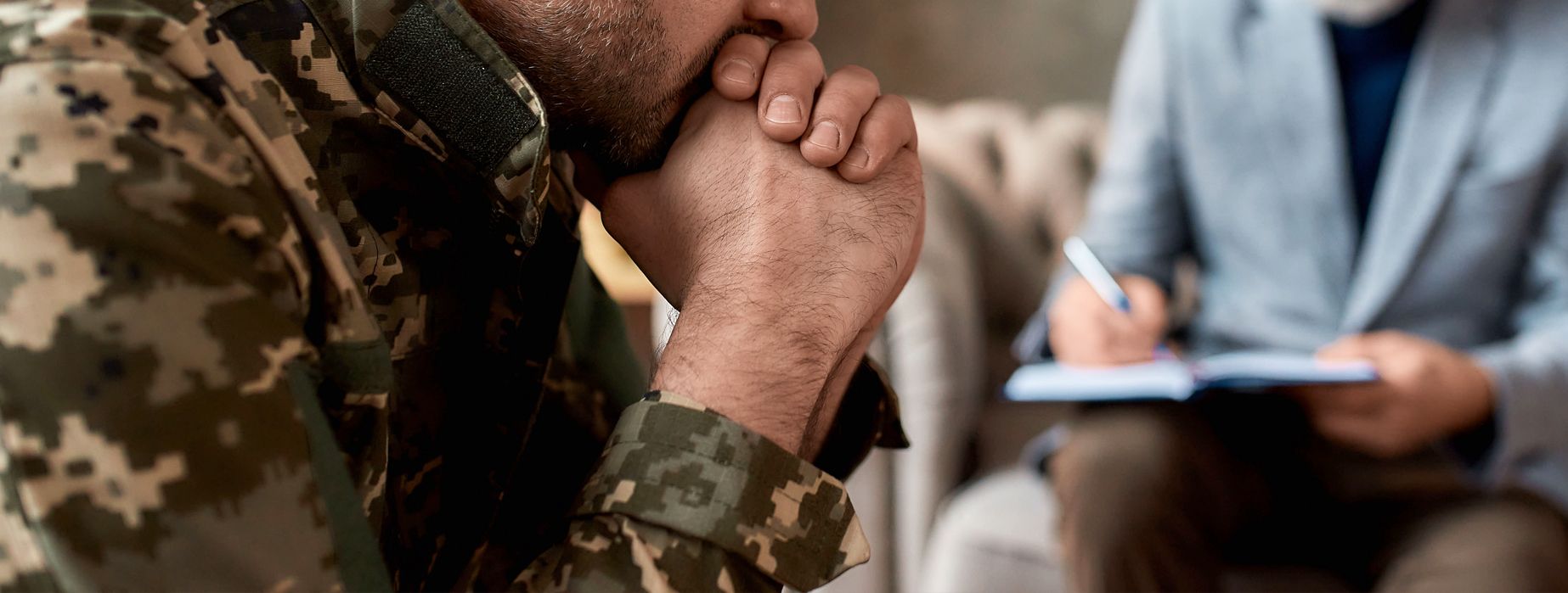 A soldier is sitting in a chair talking to a psychologist.