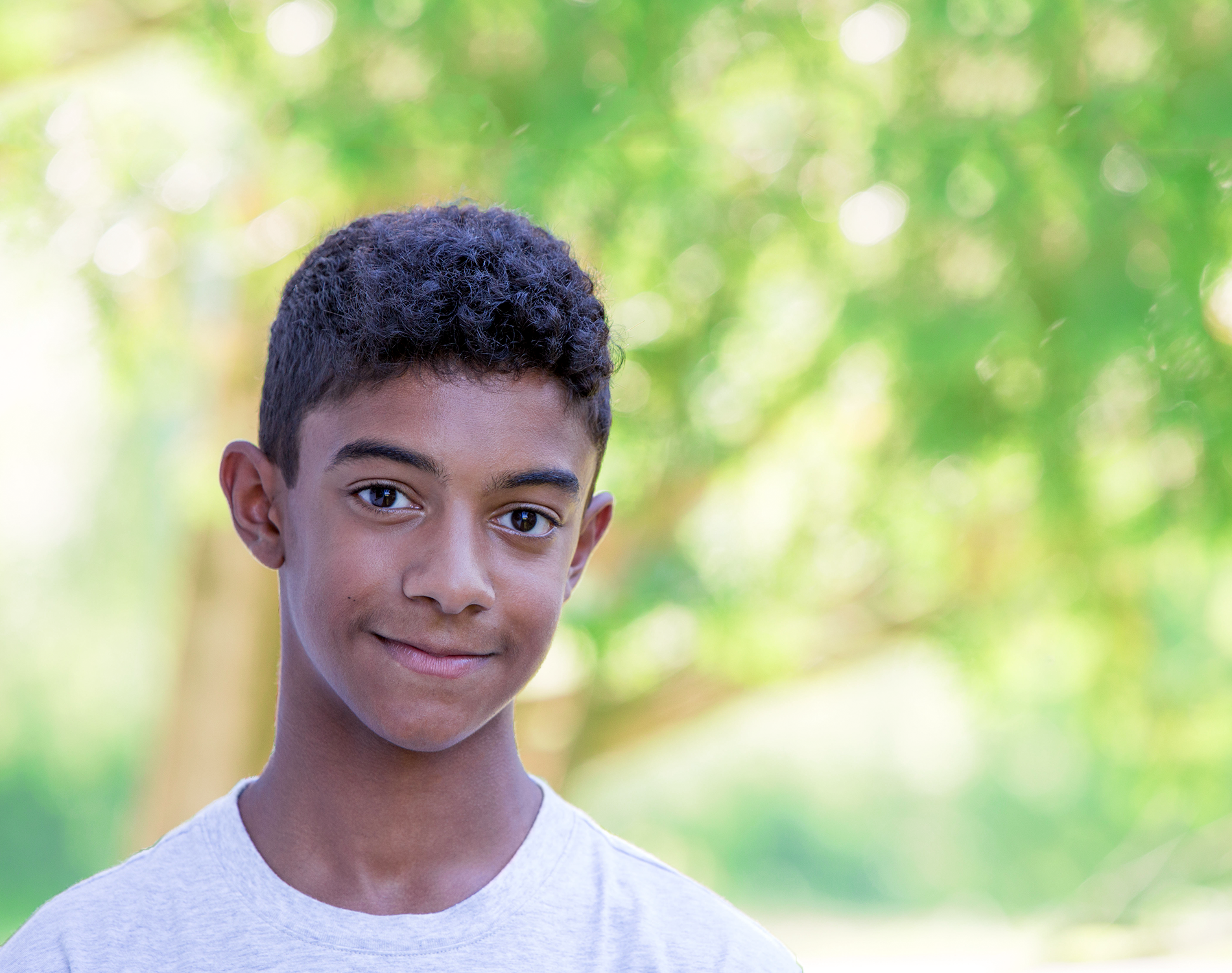 A young boy in a white shirt is smiling for the camera.
