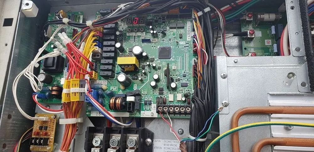 Circuit board with wires and components inside a metal enclosure.