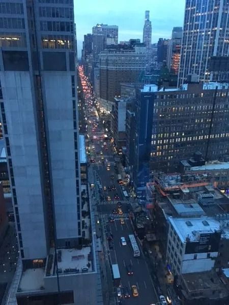 City street view, tall buildings, traffic, dusk lighting.