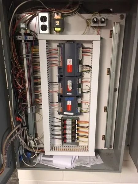 Electrical control panel with wires, PLCs, and terminal blocks.