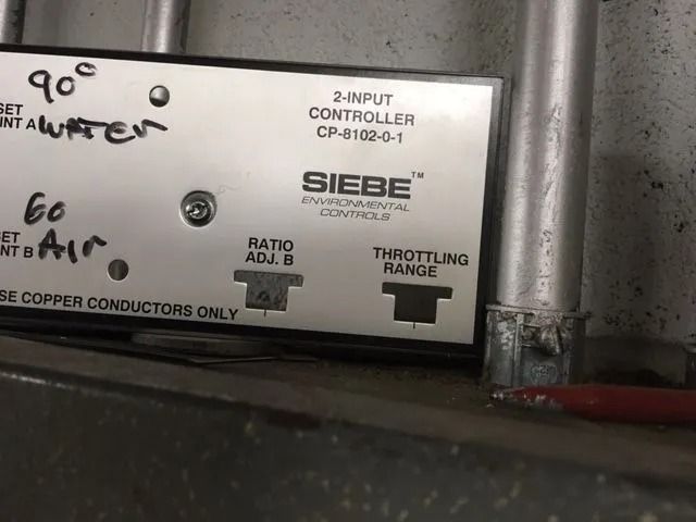 Close-up of a Siebe environmental controller with handwritten set points and adjustable settings.