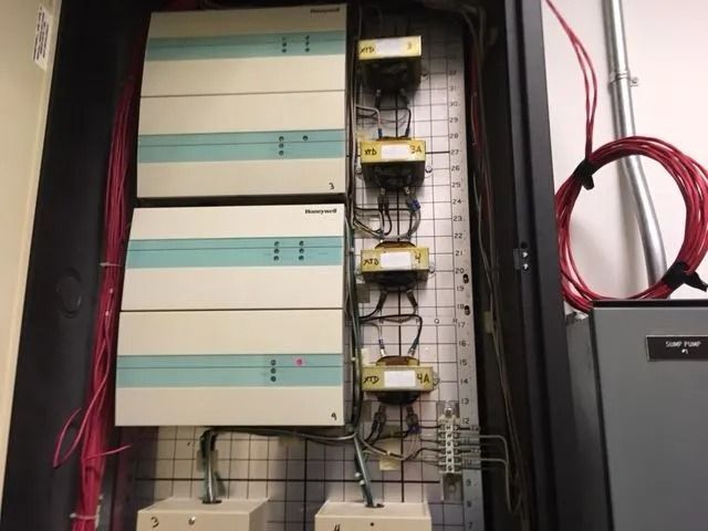 Electrical panel with white and blue boxes, transformers, and wires.