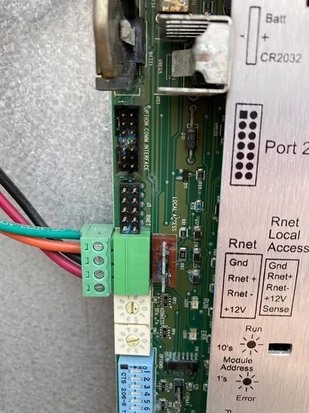 Close-up of a circuit board with various ports, terminals, and a battery slot; various wires connected.