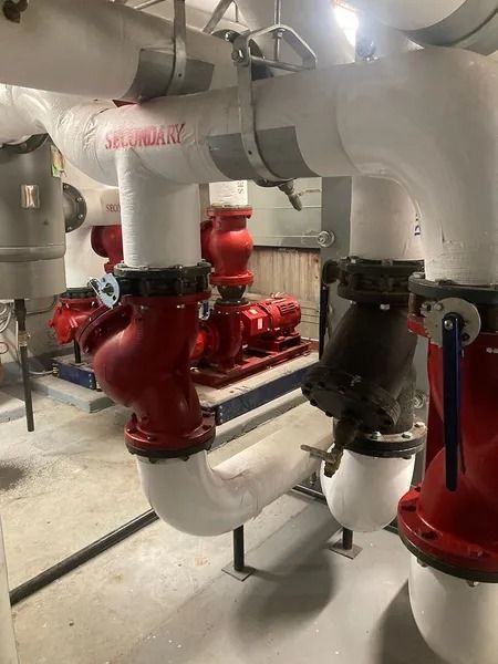 Pipes and valves in an industrial setting. Red and white pipes with black valves.