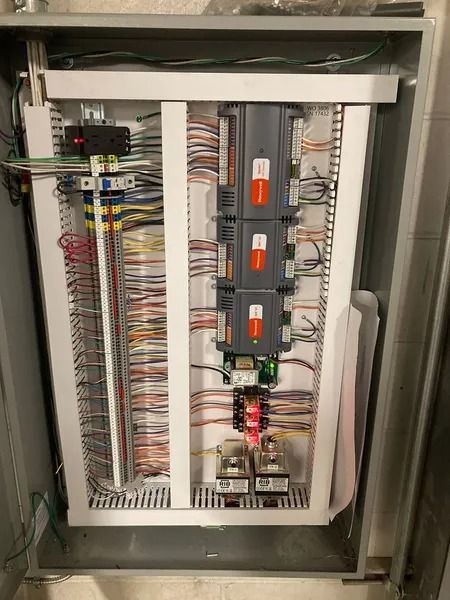 Electrical panel with wires and components. White frame, gray enclosure.
