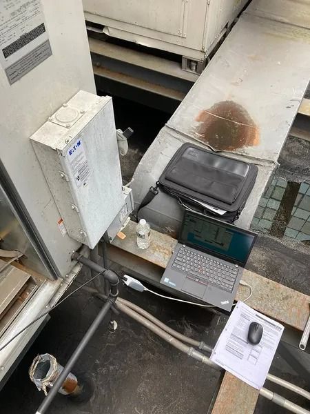 Laptop and equipment set up on a rooftop with an electrical box.