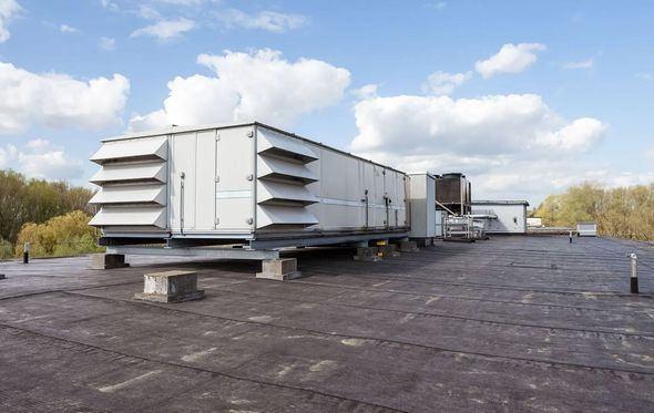 White HVAC units on a flat rooftop against a cloudy sky.