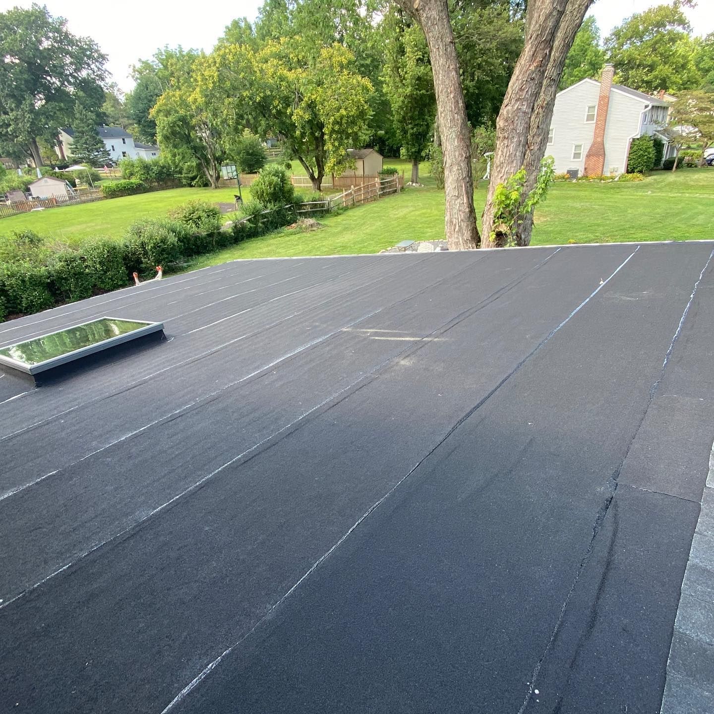 A black roof with a skylight on top of it.
