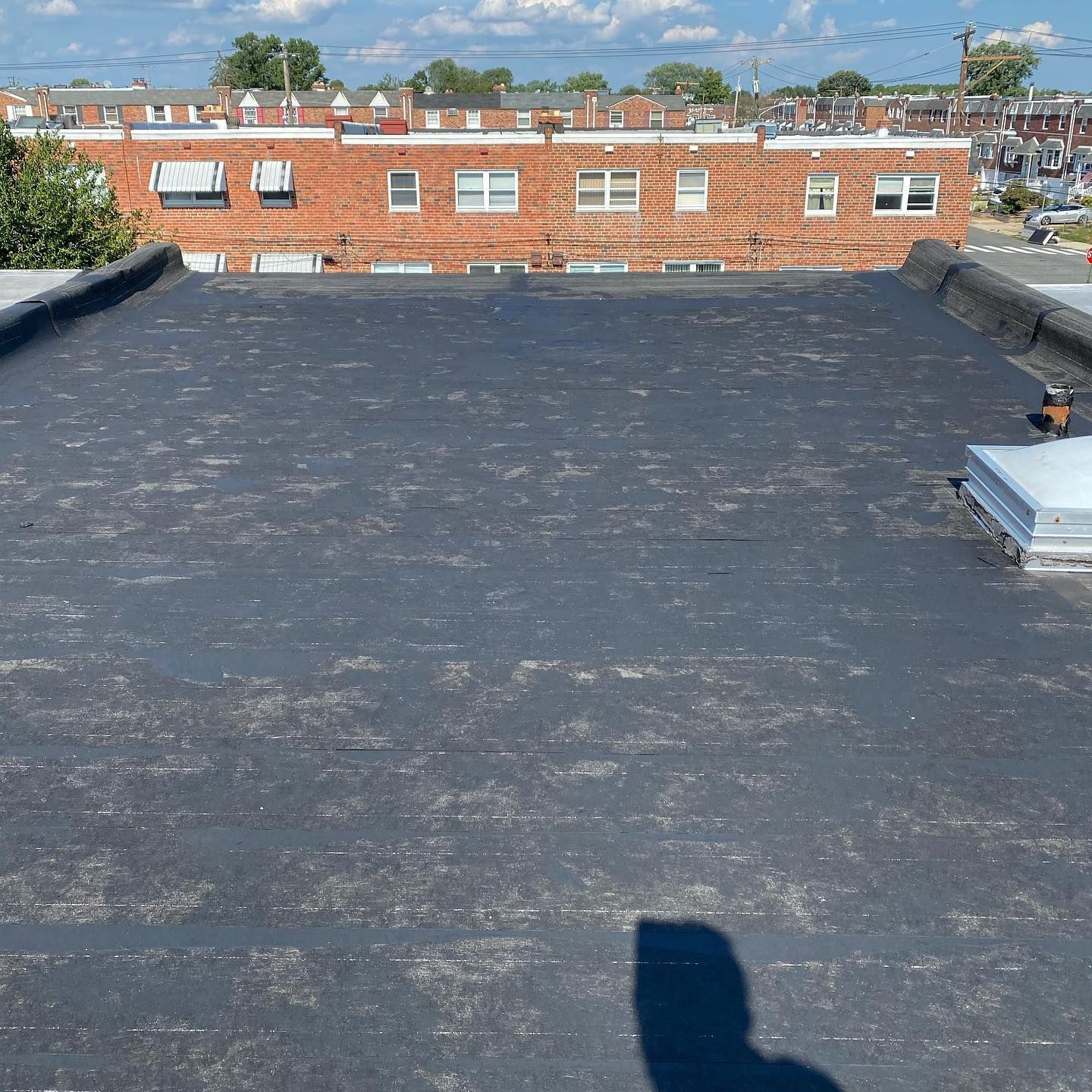 A black roof with a brick building in the background