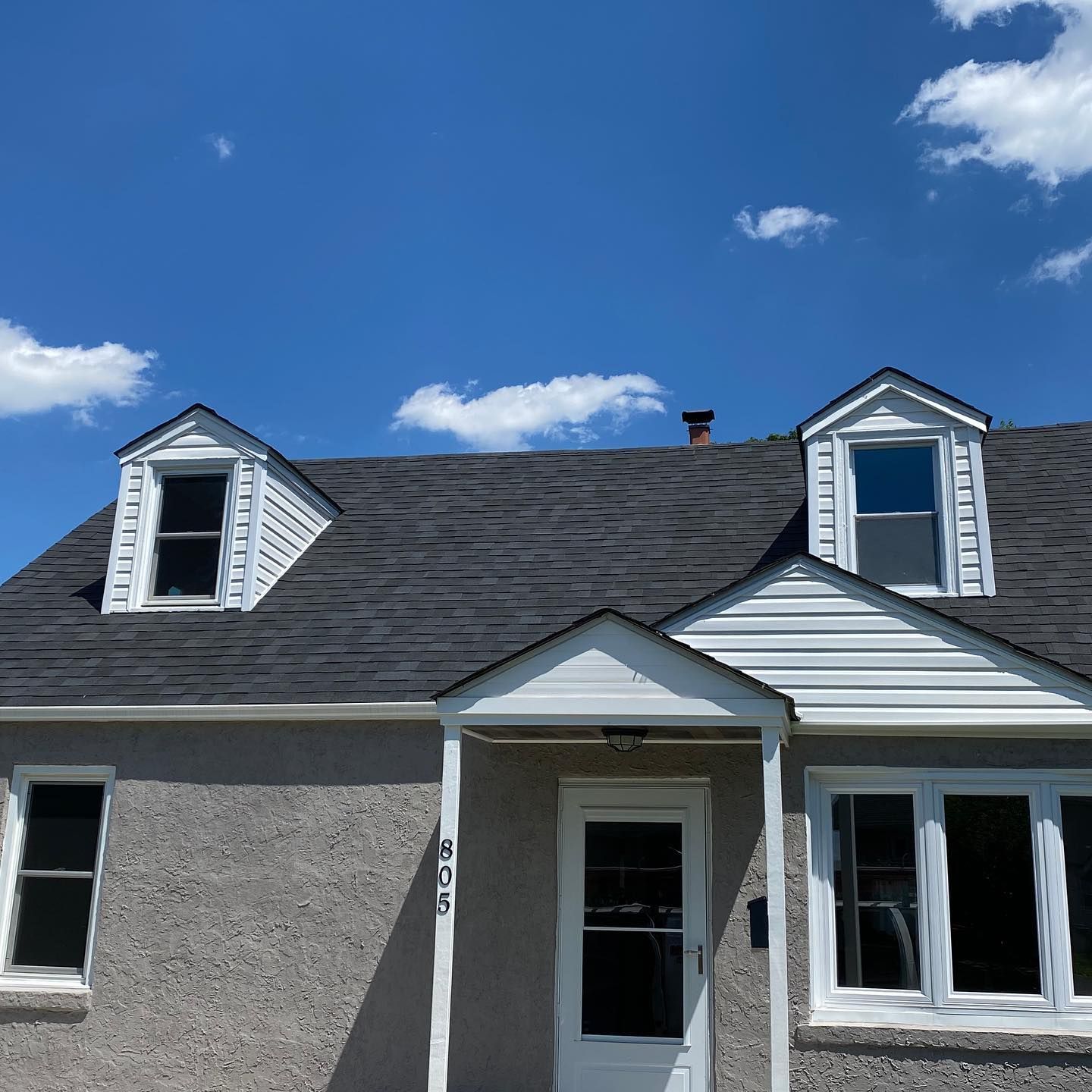 A house with a black roof and a white door
