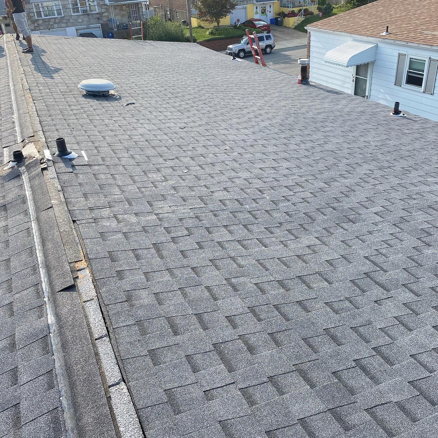 A roof with a lot of shingles on it and a house in the background.