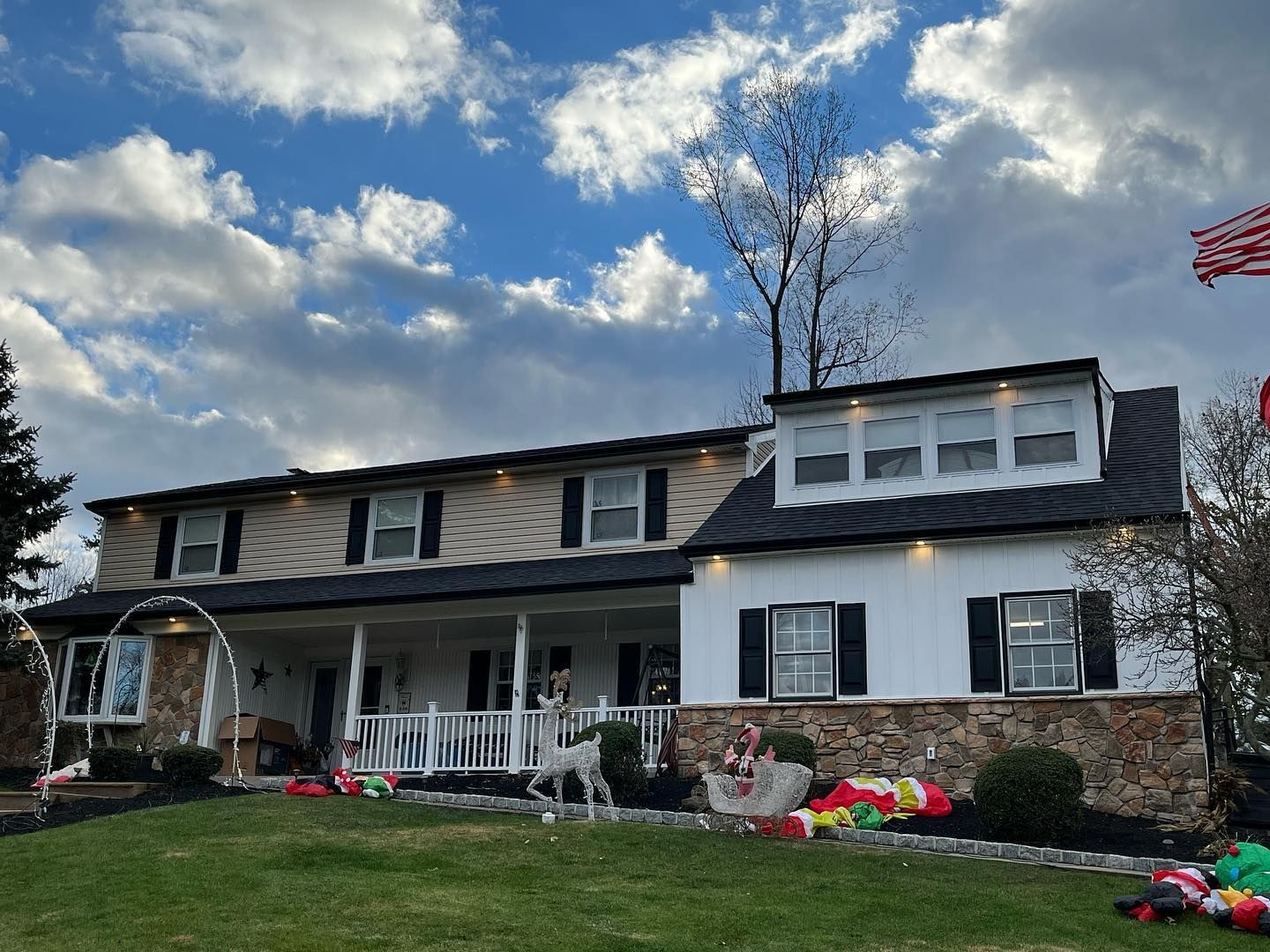 A large white house with a black roof is decorated for christmas.