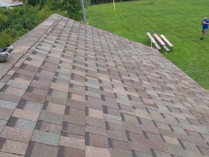 A roof with a lot of shingles is sitting on top of a lush green field.