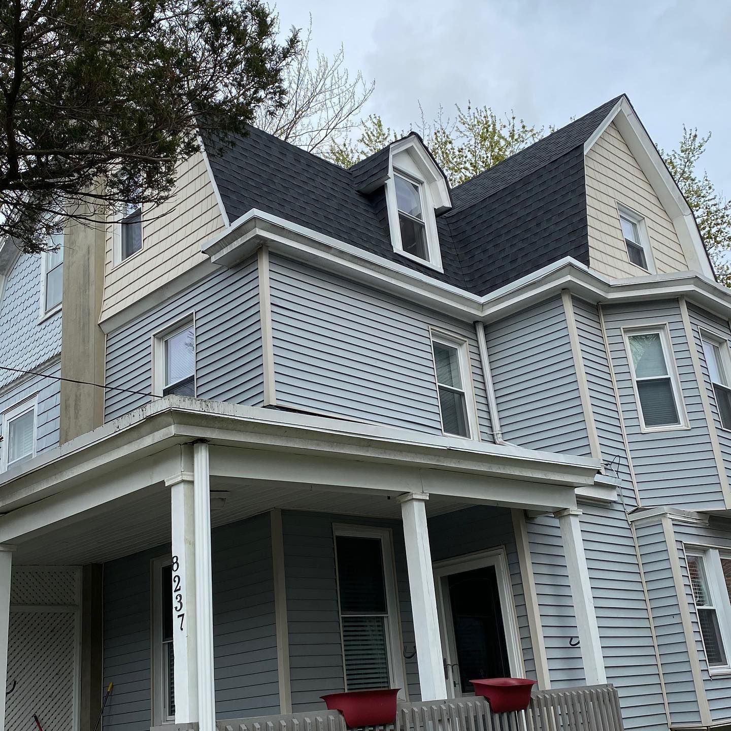 A large house with a porch and a black roof.