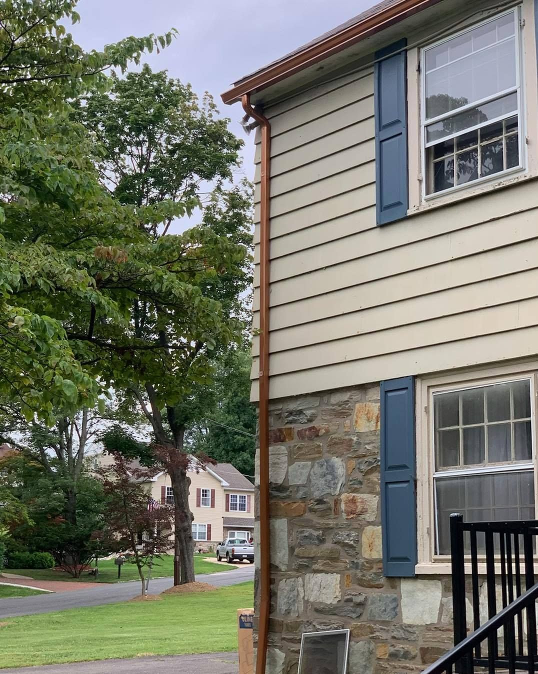 A white house with blue shutters and a stone wall