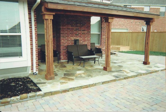 A patio with a couch and chairs under a wooden roof