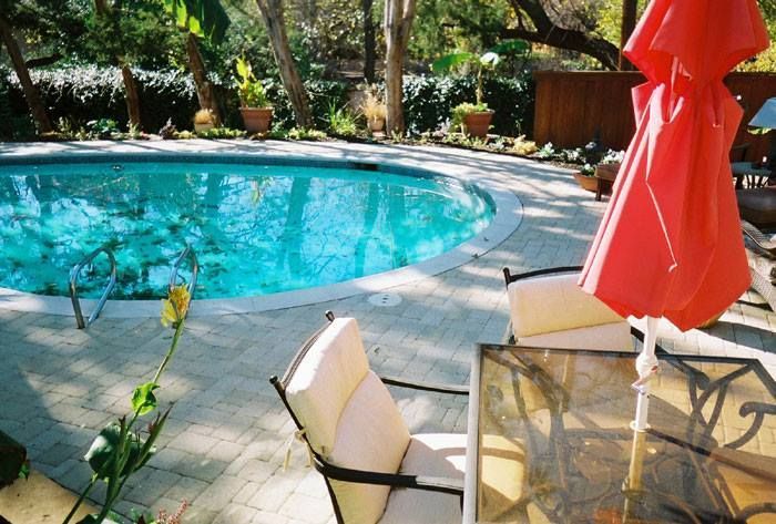 A swimming pool with a red umbrella in front of it