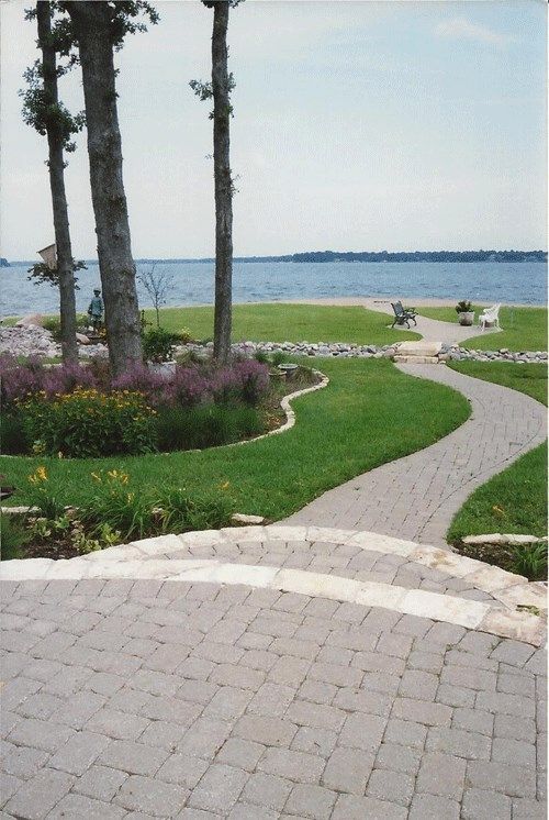 A brick walkway leading to a lake with trees in the background