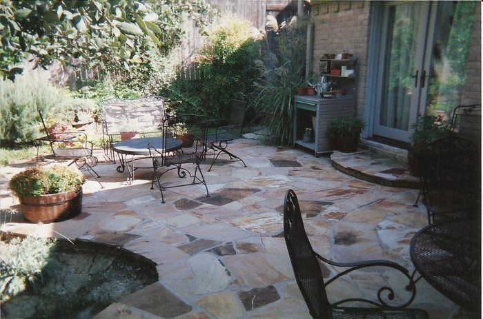 A patio with a table and chairs and potted plants