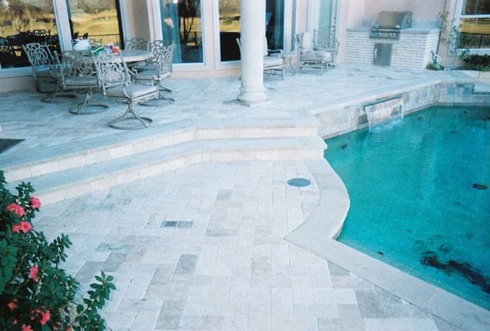 A patio with a table and chairs next to a swimming pool