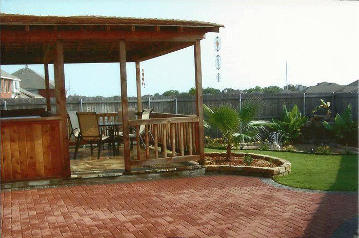 A wooden gazebo with a brick patio in front of it