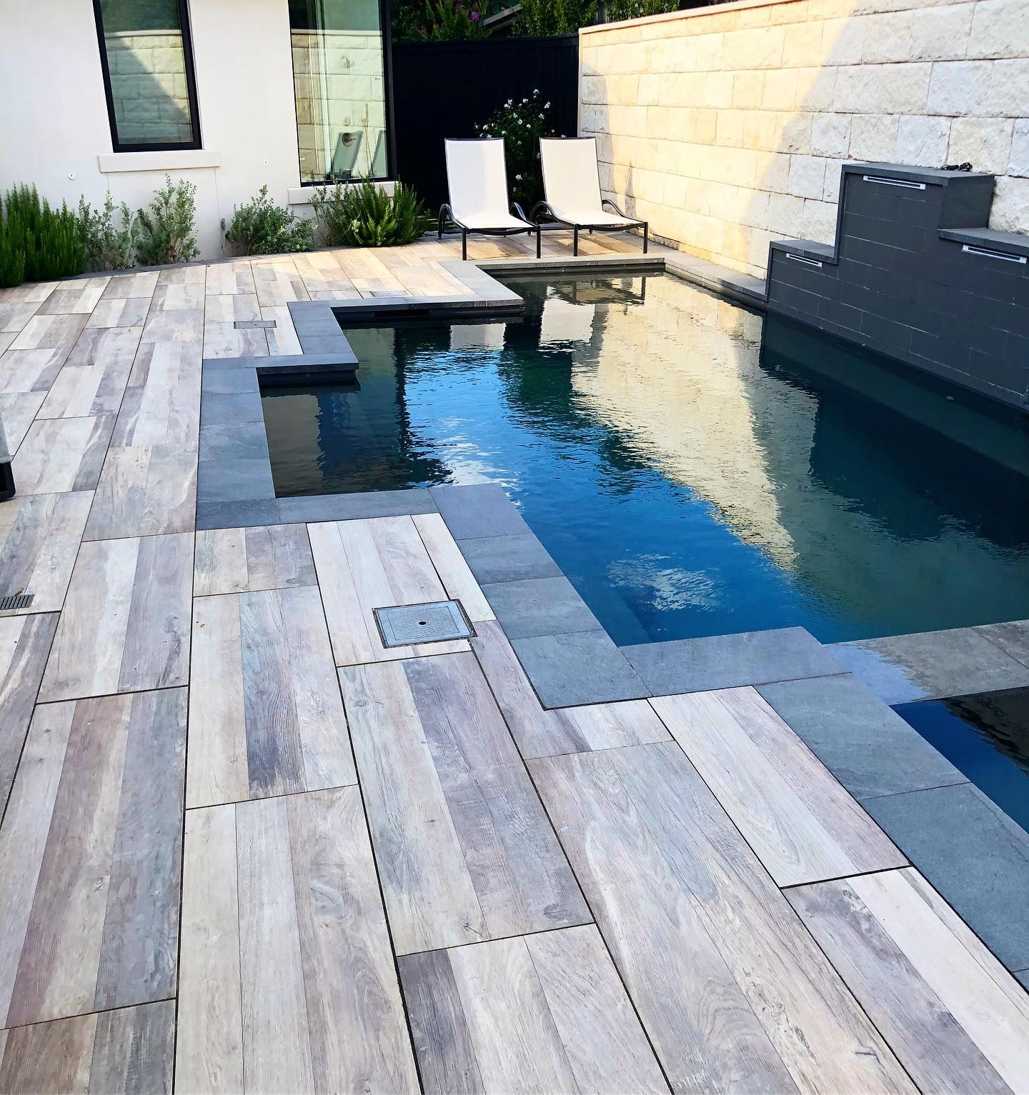 A large swimming pool is surrounded by a wooden deck