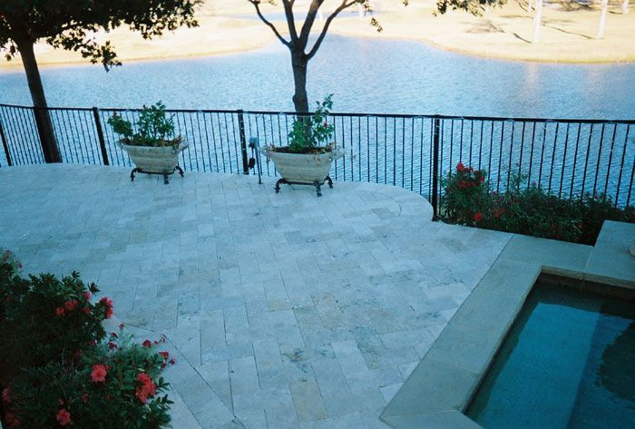 a patio with potted plants and a pool overlooking a lake