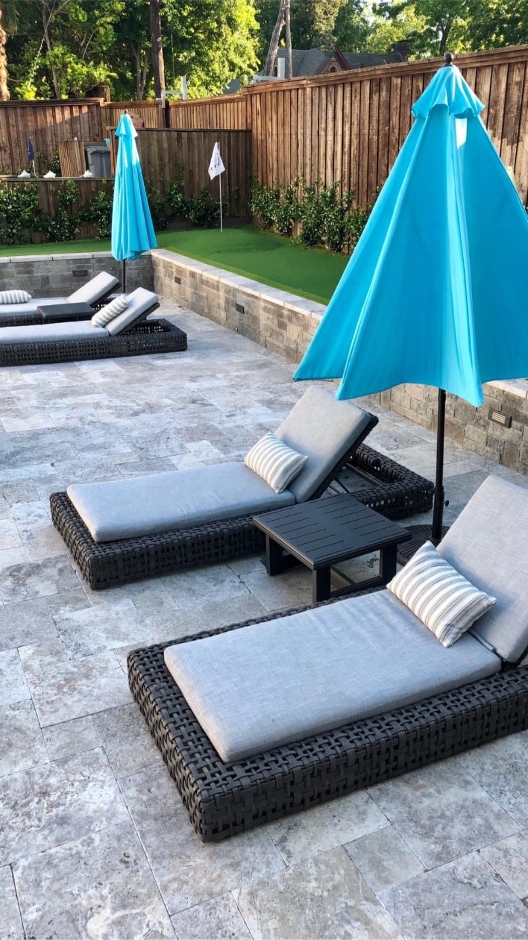 A row of lounge chairs with blue umbrellas on a patio.
