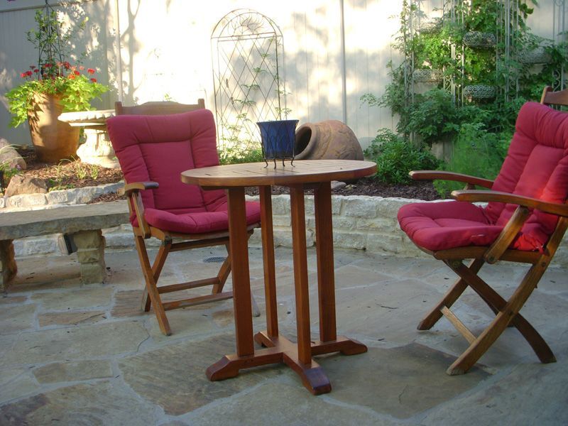 a table and chairs on a patio with red cushions