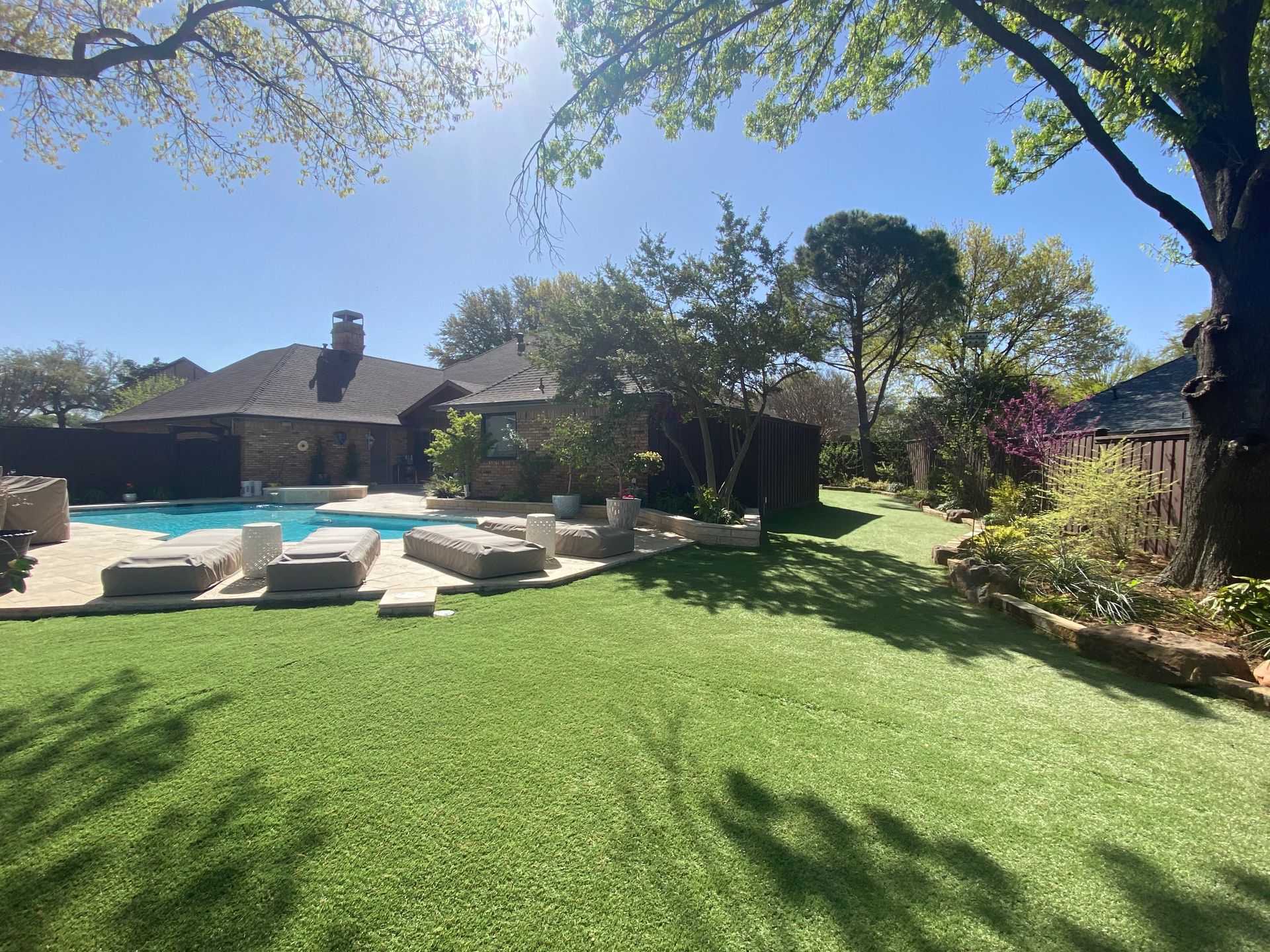 There is a large swimming pool in the backyard of a house.