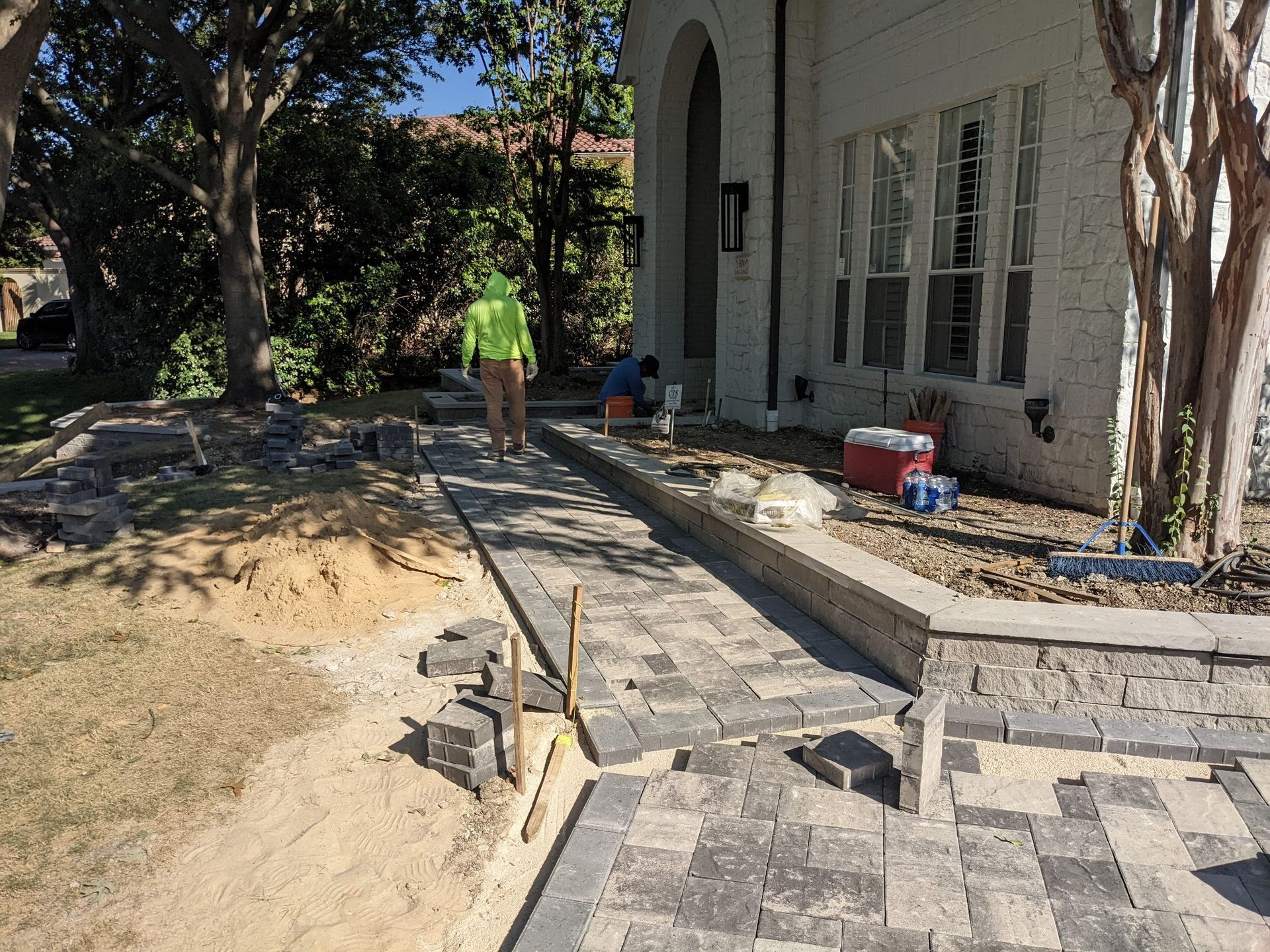 A man in a yellow vest is walking down a sidewalk in front of a house.