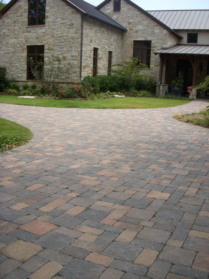 a brick driveway leading to a large stone house .