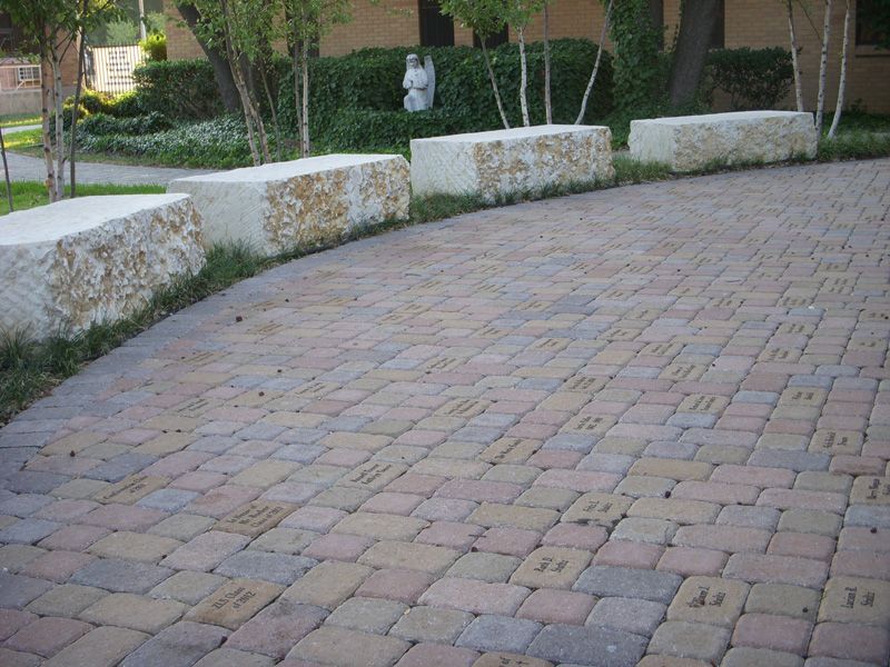 a brick driveway with a stone wall in the background