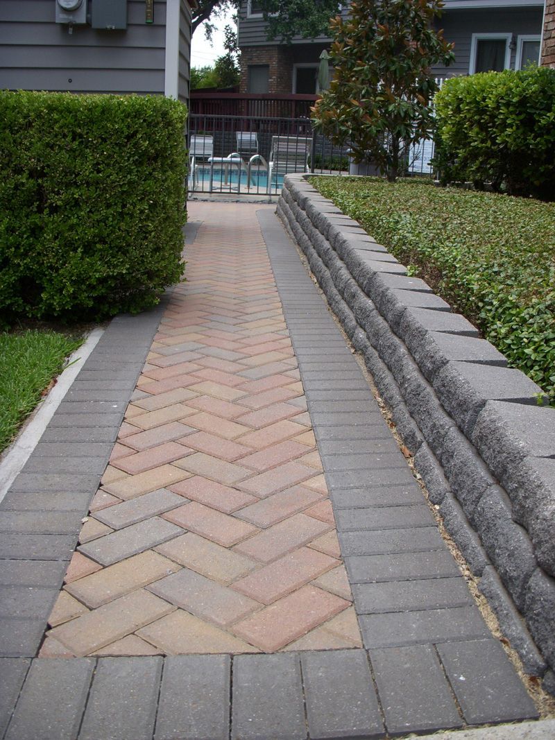 a brick walkway with a pool in the background