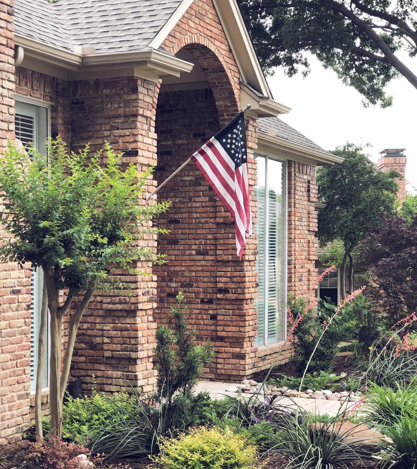 an american flag is flying in front of a brick house