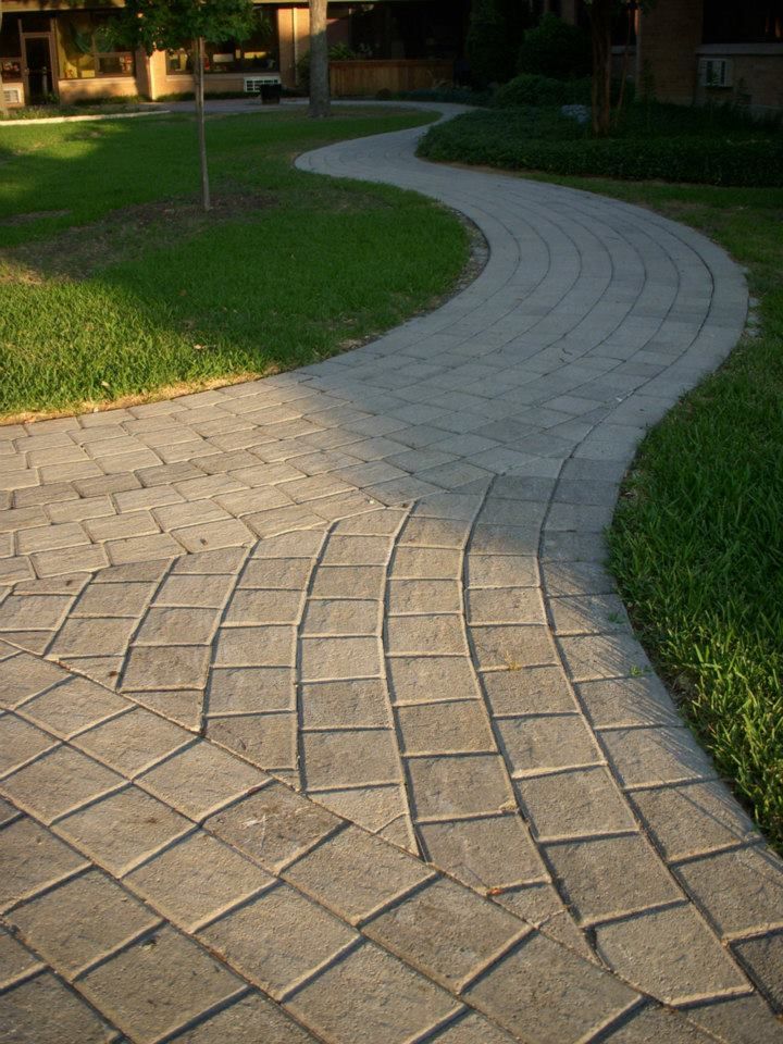 a brick walkway going through a grassy area