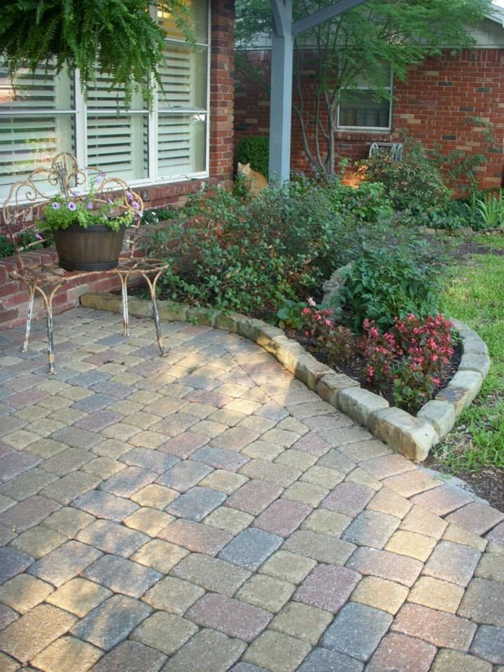 a brick patio with a bench and flowers in front of a brick house .