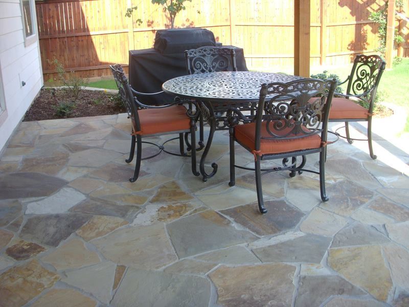a patio with a table and chairs and a grill