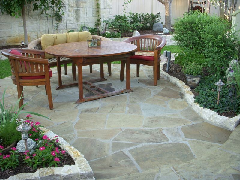 a patio with a table and chairs in a garden