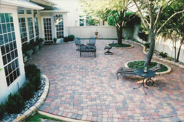 a brick patio with chairs and a table in front of a house