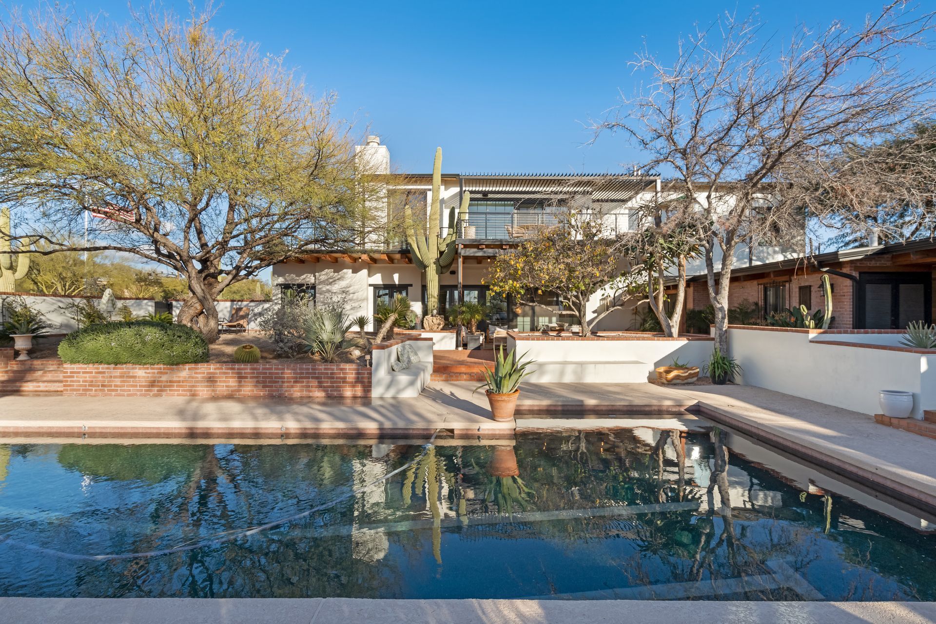 A large swimming pool is in front of a large house.