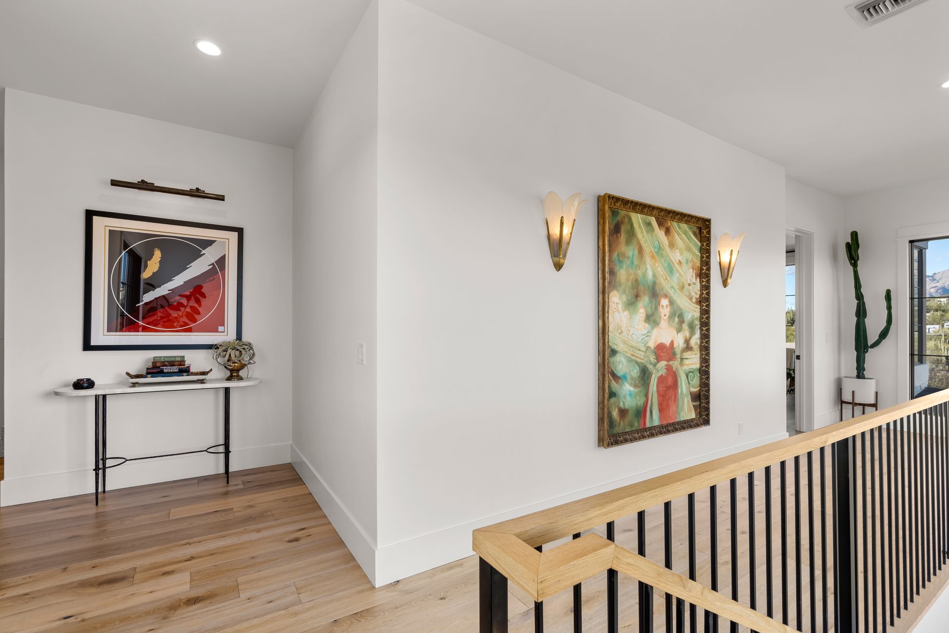A hallway with a wooden railing and a painting on the wall.