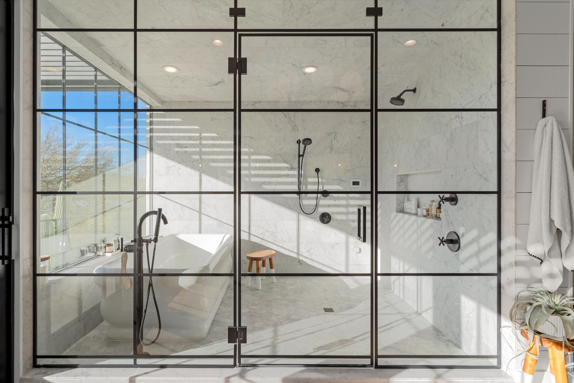 A bathroom with a large glass shower door and a bathtub.