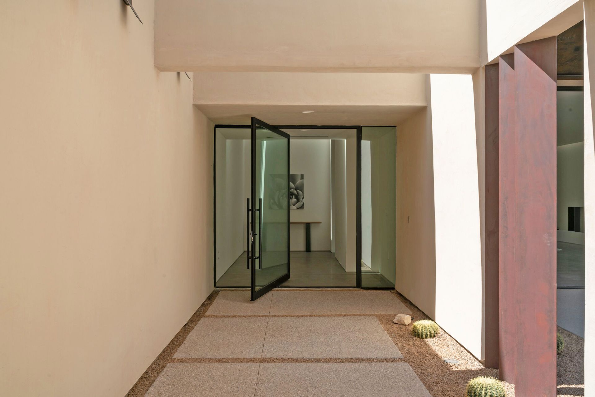 A modern house with a large glass door and a walkway leading to it.